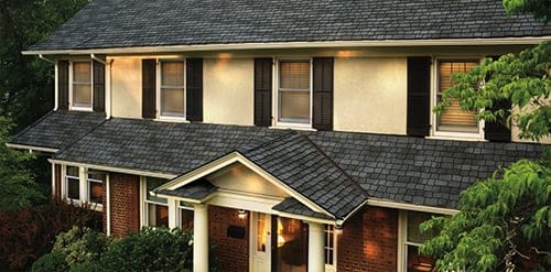 A large house with a porch and trees. The house has two stories.