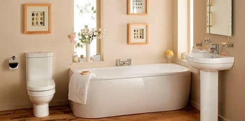 A clean and modern bathroom with a white bathtub, toilet, and sink. The bathtub is accompanied by a towel.