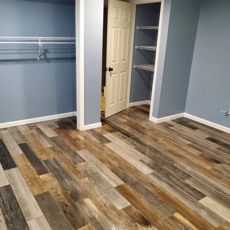 An empty room with blue walls and a wooden floor. The room has a closet with shelves.